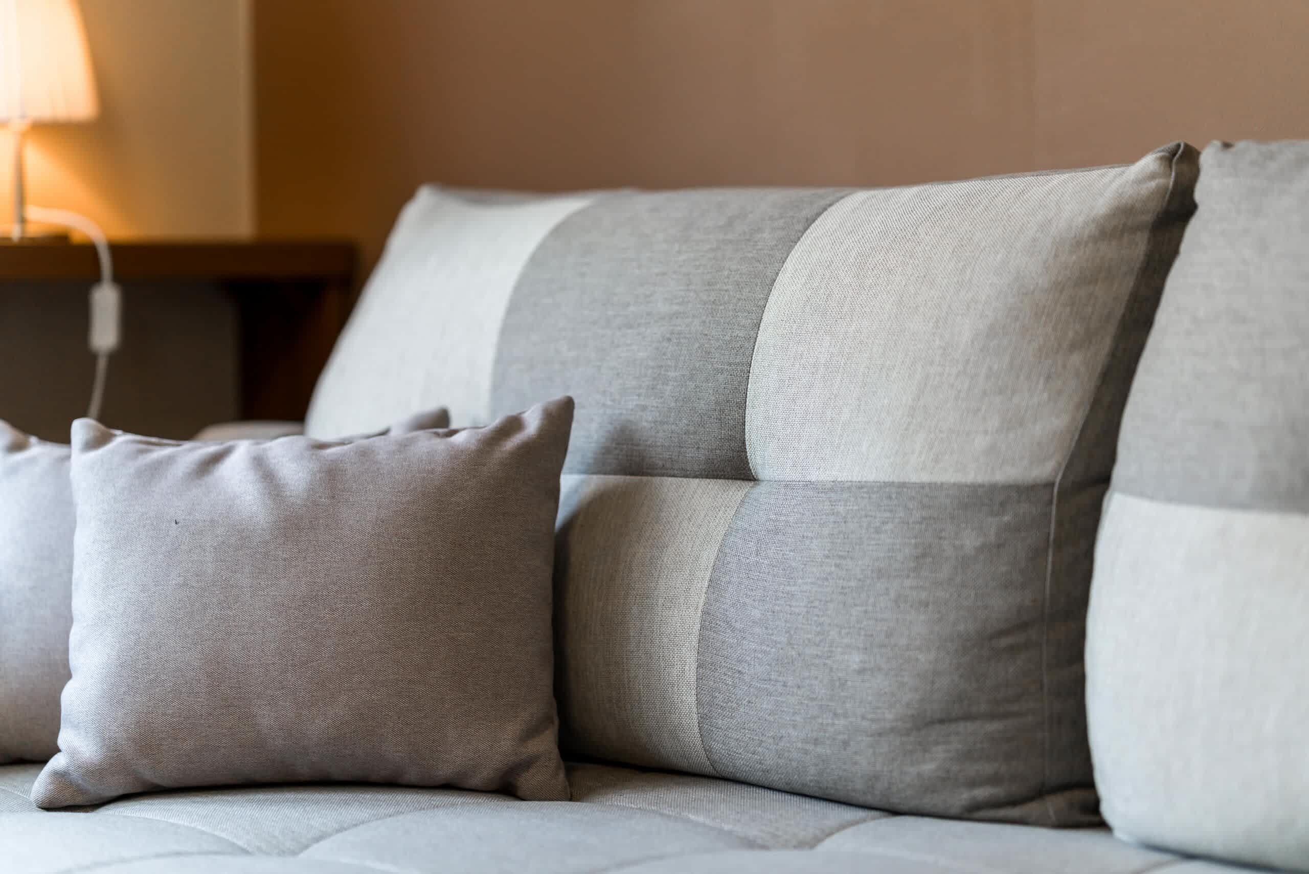 A close-up of a sofa with multiple cushions in a neutral color palette.