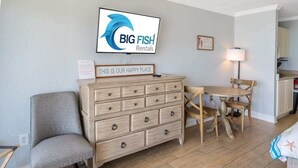 Olohuoneessa on puinen lipasto, televisio, jossa näkyy elokuvan «Big Fish» vuokrauspalvelun logo, ruokapöytä tuoleineen sekä kyltti, jossa lukee: «TÄMÄ ON MEIDÄN ONNELLINEN PAIKKA».