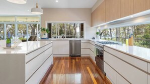 Une cuisine moderne dotée de grandes fenêtres, d’un plancher en bois et de meubles blancs.