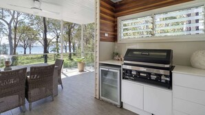 Une cuisine moderne dotée d’un barbecue intégré et de grandes fenêtres donnant sur un espace extérieur agréable.