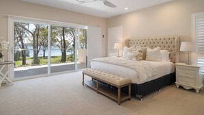 Une chambre avec un grand lit, un banc, un ventilateur de plafond et une vue sur l’extérieur.