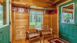 A wooden cabin interior with two wooden chairs, a window, and a green door. - Alpine Star Lodge (West Yellowstone)