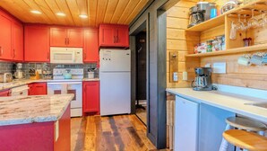 Keittiössä on puukehikoiset kaapit, mikroaaltouuni, jääkaappi ja kahvinkeitin.