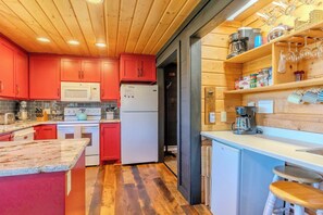 Eine Küche mit Holzausstattung, einer Mikrowelle, einem Kühlschrank und einer Kaffeemaschine.