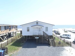 A white house with a porch and a staircase leading to a pier.
