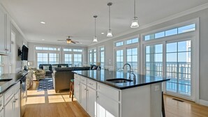 Una cocina amplia con una isla grande, un comedor con sofá y vista al mar.