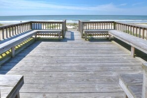 Un muelle de madera que conduce a una playa con bancos y barandillas.