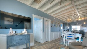 Un vaste espace de vie doté d’un plancher en bois, d’une table à manger avec des chaises, et d’une cuisine moderne en arrière-plan.