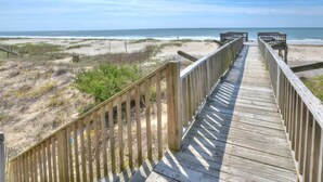 Une promenade en bois qui mène à la plage et offre une vue dégagée sur l’océan.