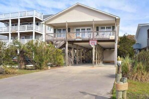 A two-story building with a balcony, a basketball hoop, and a gated entrance.