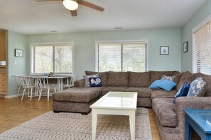 A living room with a sectional sofa, a coffee table, and a dining area with chairs and a table.
