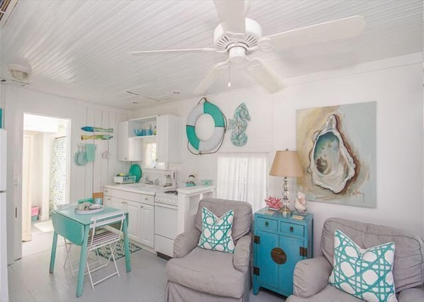 A bright, white interior with a kitchen, dining area, and seating.