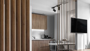 Une cuisine moderne avec des meubles en bois, un coin repas comprenant une table et des chaises, et un téléviseur à écran plat fixé au mur.
