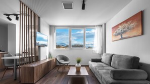 Un salon moderne avec un canapé, une table basse, un téléviseur et un tableau accroché au mur.
