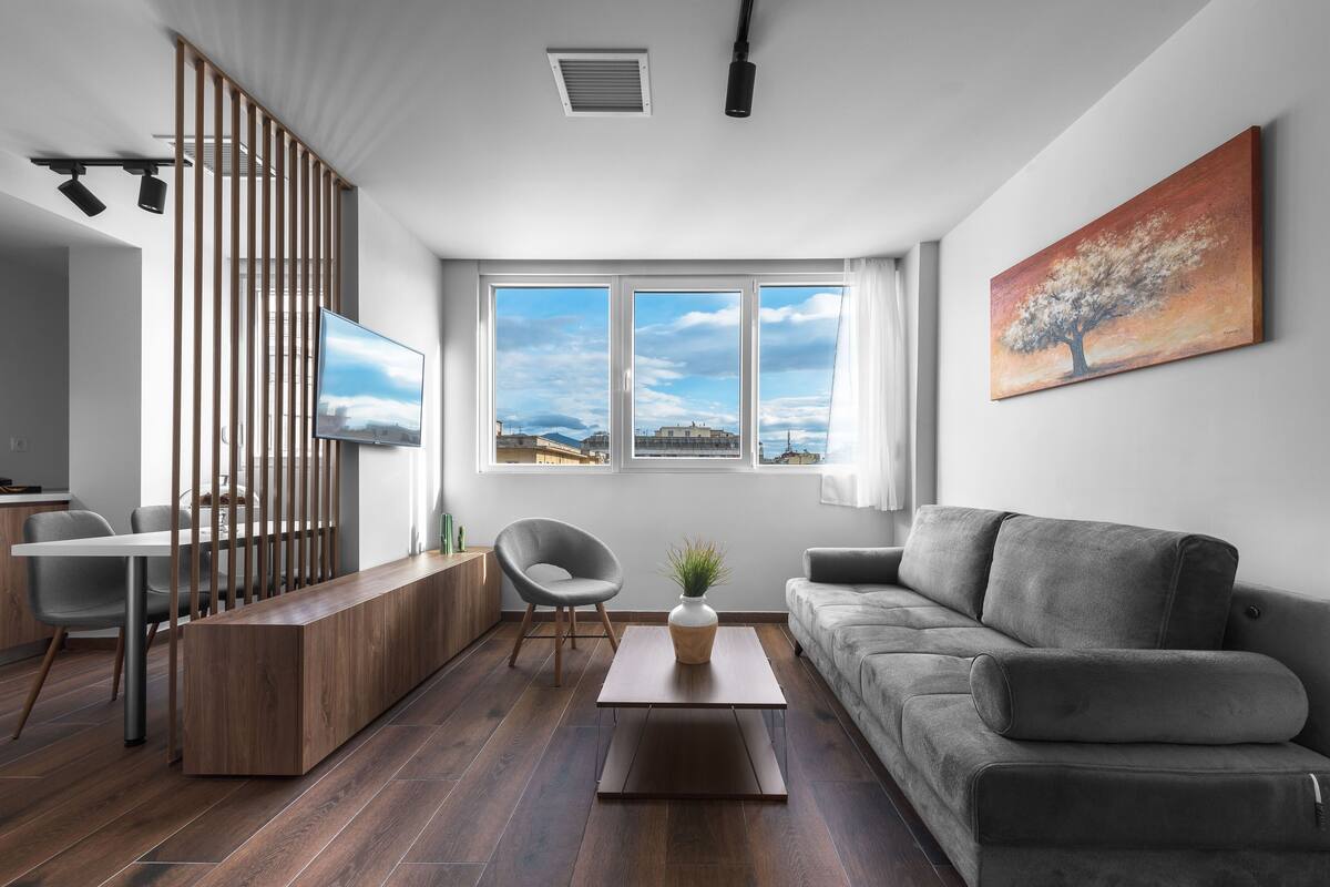 Una sala de estar moderna con un sofá, una mesa de centro, un televisor y un cuadro en la pared.