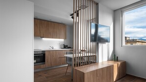 Une cuisine moderne avec des meubles en bois, un four encastré et une grande fenêtre donnant sur la ville.