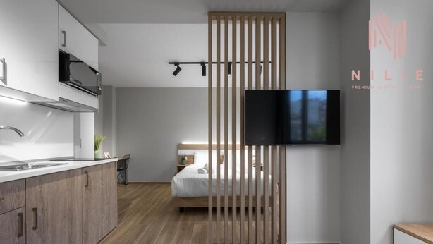 Une chambre d’hôtel moderne équipée d’une kitchenette, d’un lit, d’une télévision et d’une porte coulissante.