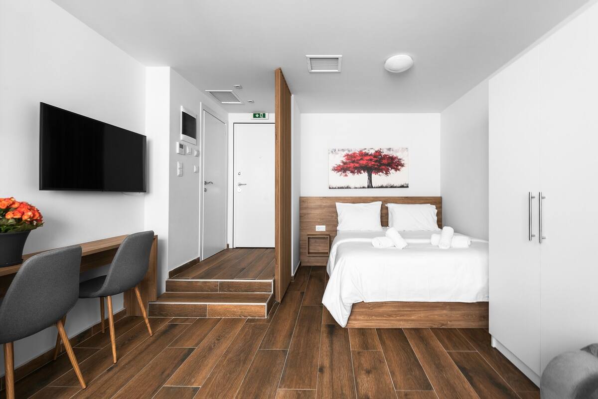 Una habitación de hotel moderna con cama, mesita de noche y televisor montado en la pared.