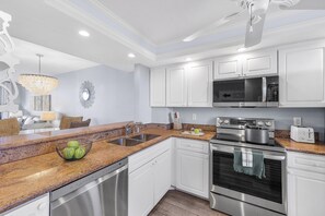 A modern kitchen with white cabinets, stainless steel appliances, and a granite countertop.