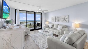 Een moderne woonkamer met balkon, witte meubels en kunst aan de wanden.