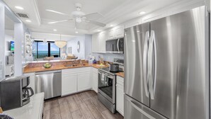 Een moderne keuken met roestvrijstalen apparatuur, witte kastjes en een houten aanrecht.