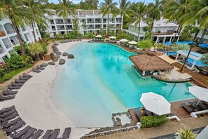 A resort with a large pool, lounge chairs, and palm trees.
