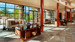 A spacious lobby with large windows, a stone floor, and a modern seating area with a sofa and coffee table.
