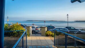 Ein Parkplatz am Wasser mit Autos, einem Fußweg und Blick auf das Meer.