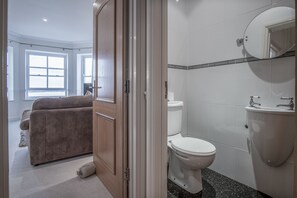 A modern bathroom with a toilet, sink, and mirror. - South Beach View- 2 Bedroom - Tenby (Tenby)