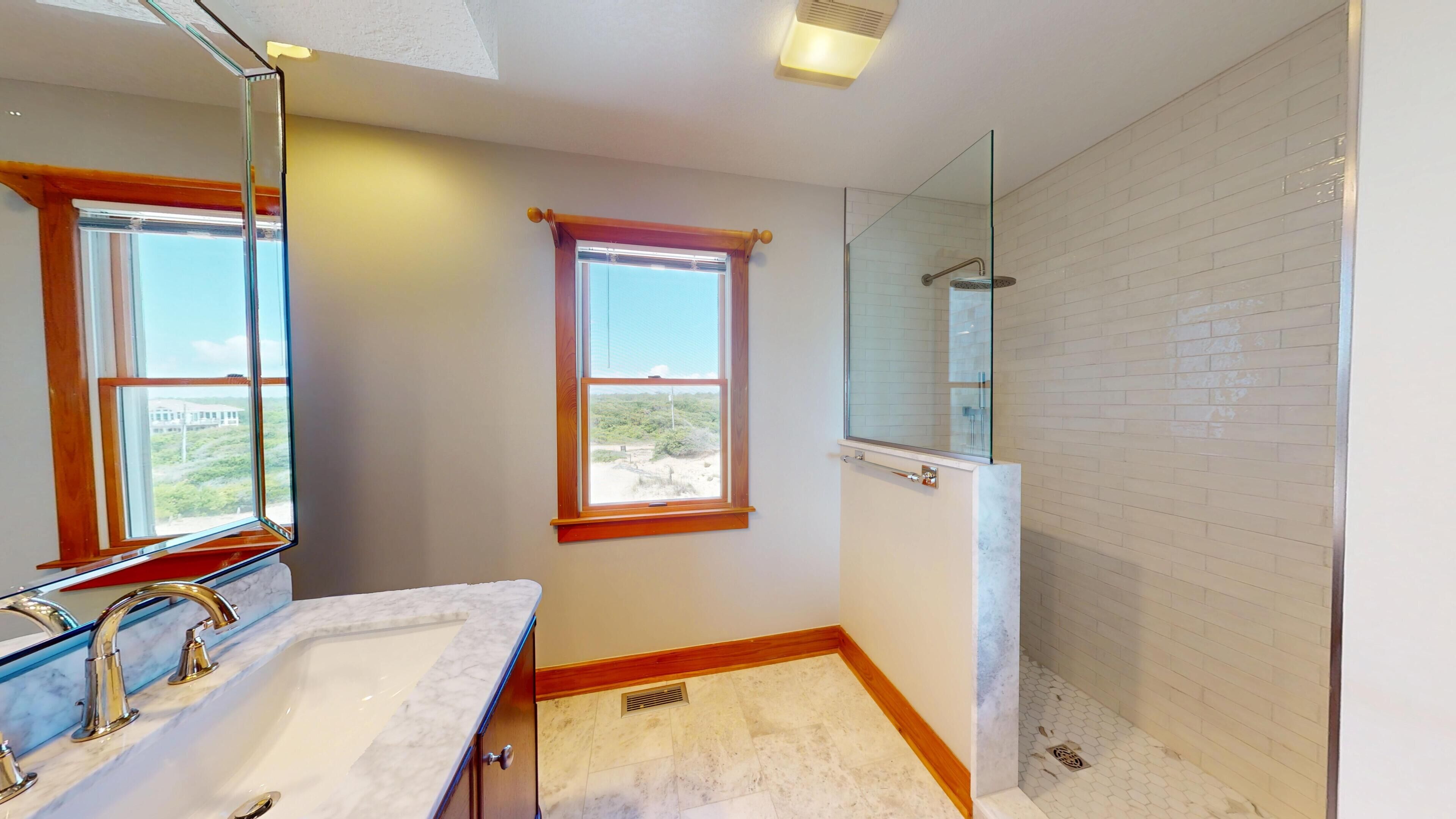 Une salle de bain avec deux lavabos, une douche et une fenêtre donnant sur un beau paysage.