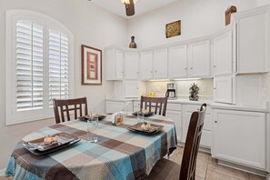 A dining area with a checkered tablecloth, white cabinets, and a kitchen in the background. - Painted Mountain Golf Retreat /On Golf Course/Private Heated Pool (Mesa)