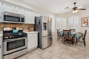 A kitchen with stainless steel appliances, white cabinetry, a dining table with chairs, and a ceiling fan. - Painted Mountain Golf Retreat /On Golf Course/Private Heated Pool (Mesa)