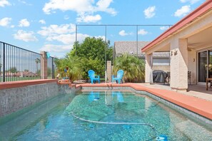 A swimming pool with clear water, surrounded by a tiled deck and a covered patio area with chairs. - Painted Mountain Golf Retreat /On Golf Course/Private Heated Pool (Mesa)