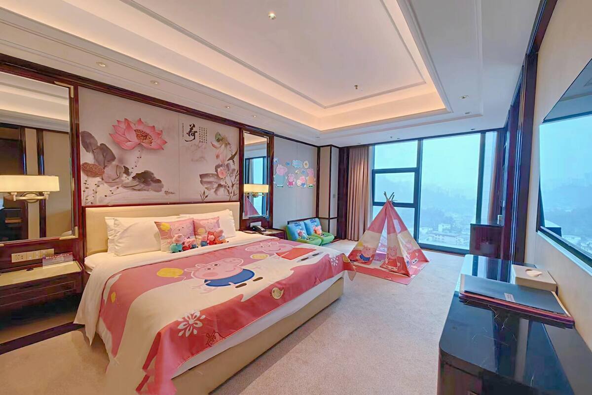 Ein Hotelzimmer mit einem großen Bett, einem Schreibtisch, einem Stuhl, einem Fenster mit Ausblick und einer Wandverzierungen.