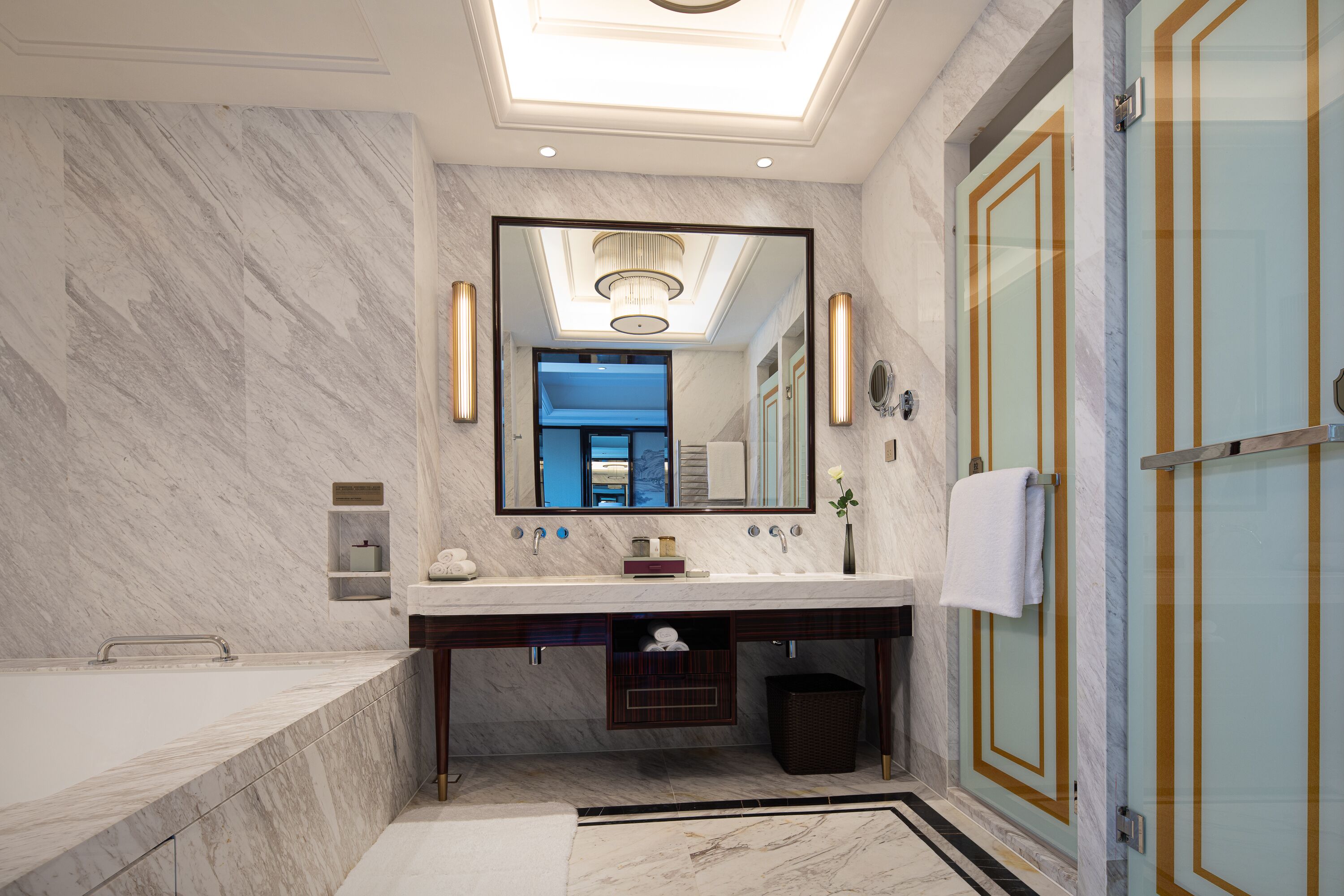 Un baño moderno con un espejo grande, lavamanos dobles, una bañera y una ducha con mampara de vidrio.