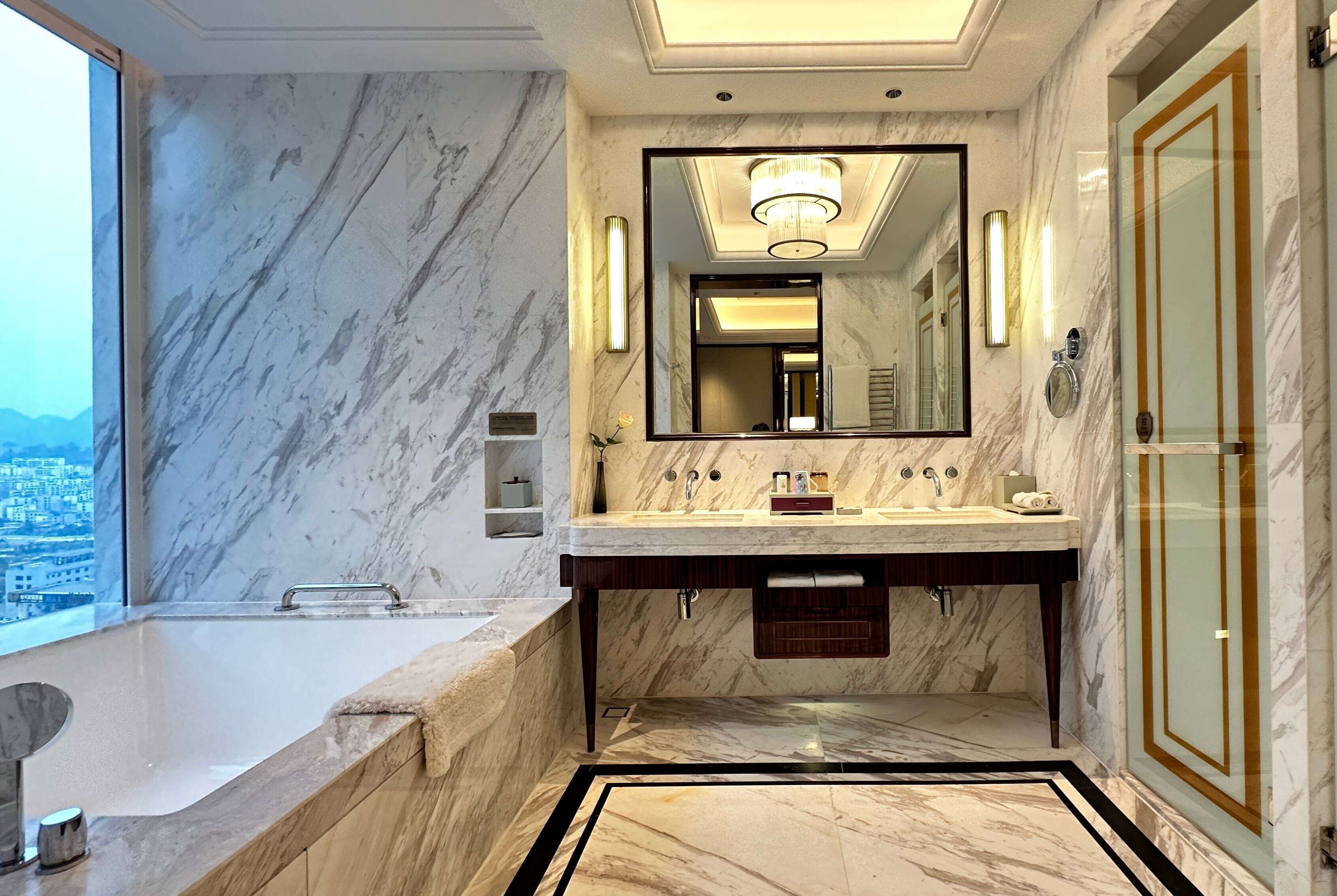 Un baño lujoso con un lavamanos grande de mármol, una bañera y un espejo grande.