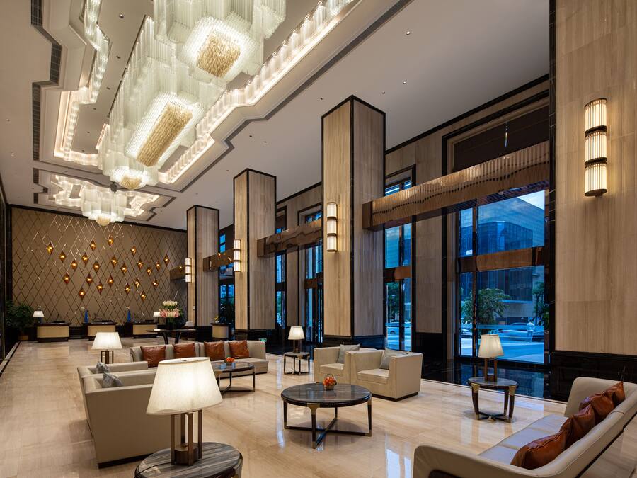 A spacious lobby with modern furnishings, large windows, and decorative lighting.
