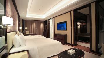 Quarto de hotel com uma cama grande, televisão, escrivaninha e guarda-roupa.