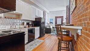 A kitchen with white cabinets, a black refrigerator, and a stove. There is a wooden chair and a rug on the floor. - Chic 2BR: Near Downtown, Copper Mountain (Leadville)