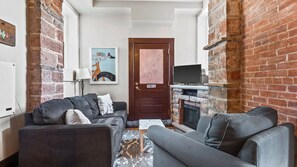 A cozy living room with a fireplace, a television, and a sofa. - Chic 2BR: Near Downtown, Copper Mountain (Leadville)