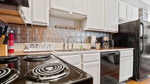 A modern kitchen with white cabinets, a black refrigerator, a gas stove, and a coffee maker. - Chic 2BR: Near Downtown, Copper Mountain (Leadville)