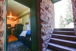 A cozy interior with a stone wall, a staircase, and a living area with a couch and a rug. - Chic 2BR: Near Downtown, Copper Mountain (Leadville)