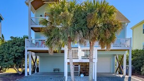 A two-story house with a balcony on the upper floor, a small porch area, and a number '150' sign. - Spacious 5 BR House with Private Pool and ICW views (Holden Beach)