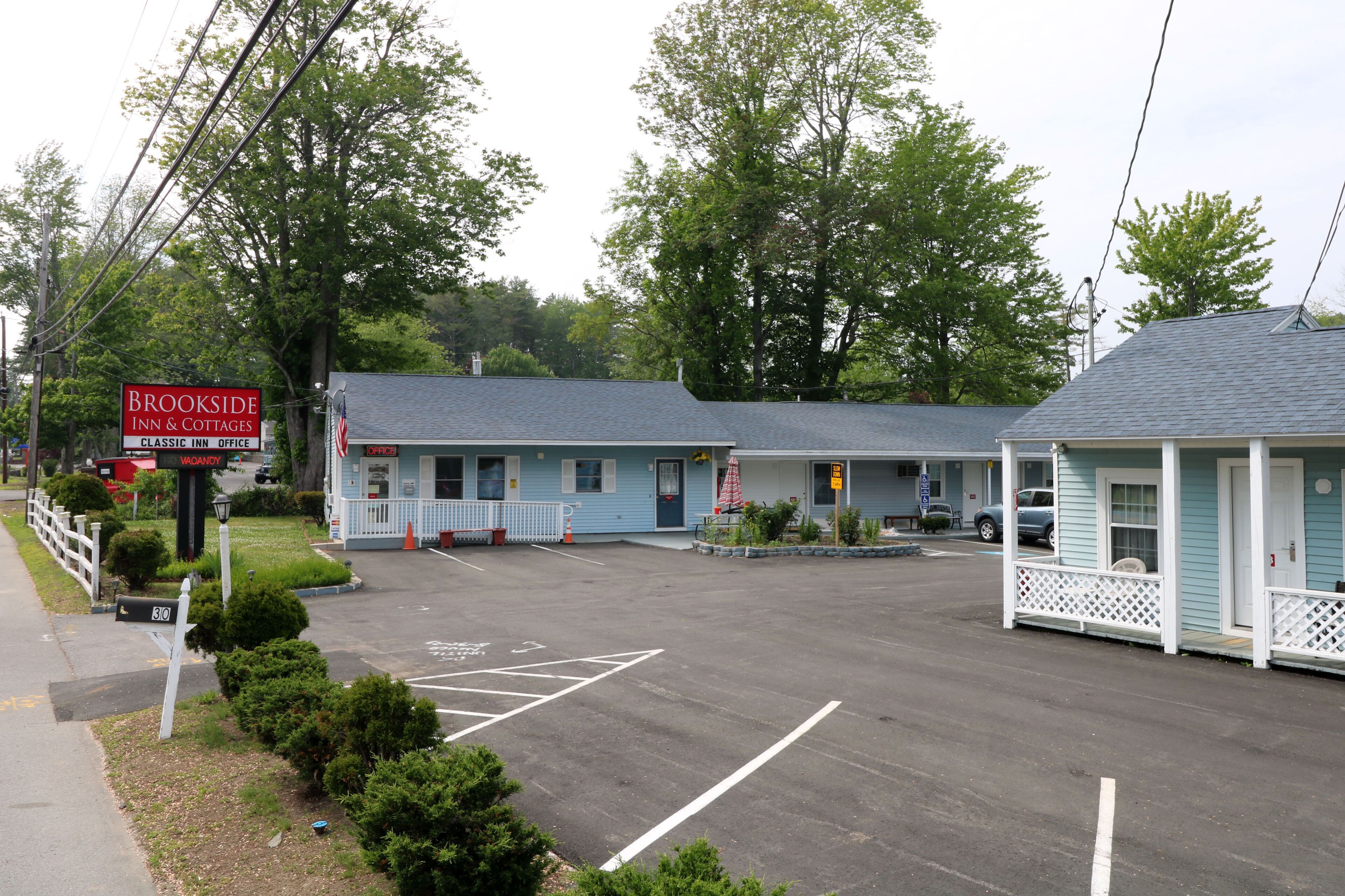 A motel with a parking lot, a mailbox, and a sign for Brookside Inn & Cottages.
