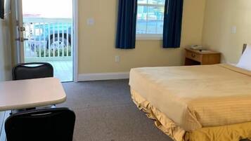 A hotel room with a bed, a desk, a chair, a window with curtains, and a view of the outside.