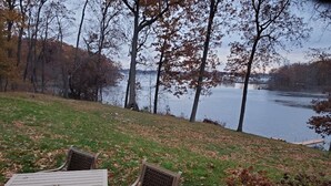 Ein Außenbereich mit Tisch und Stühlen mit Blick auf einen See, im Hintergrund Bäume.