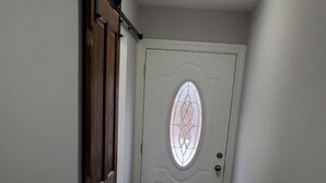 Ein Korridor mit einer Holztür und einem satinierten Fenster.