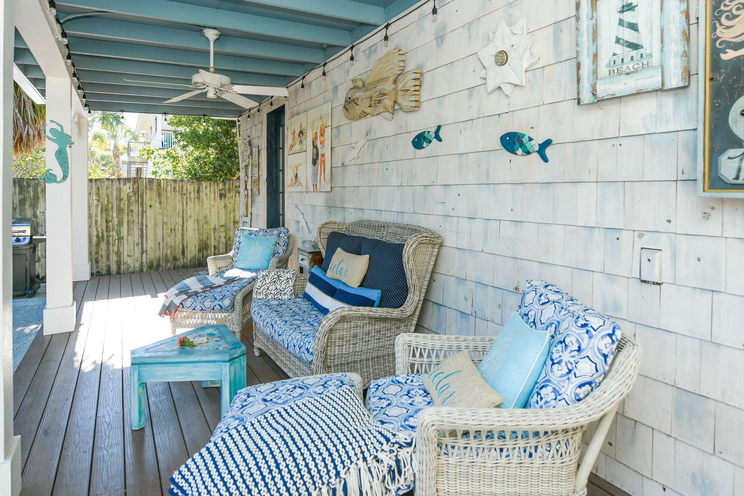 A covered outdoor seating area with wicker furniture and blue patterned cushions.