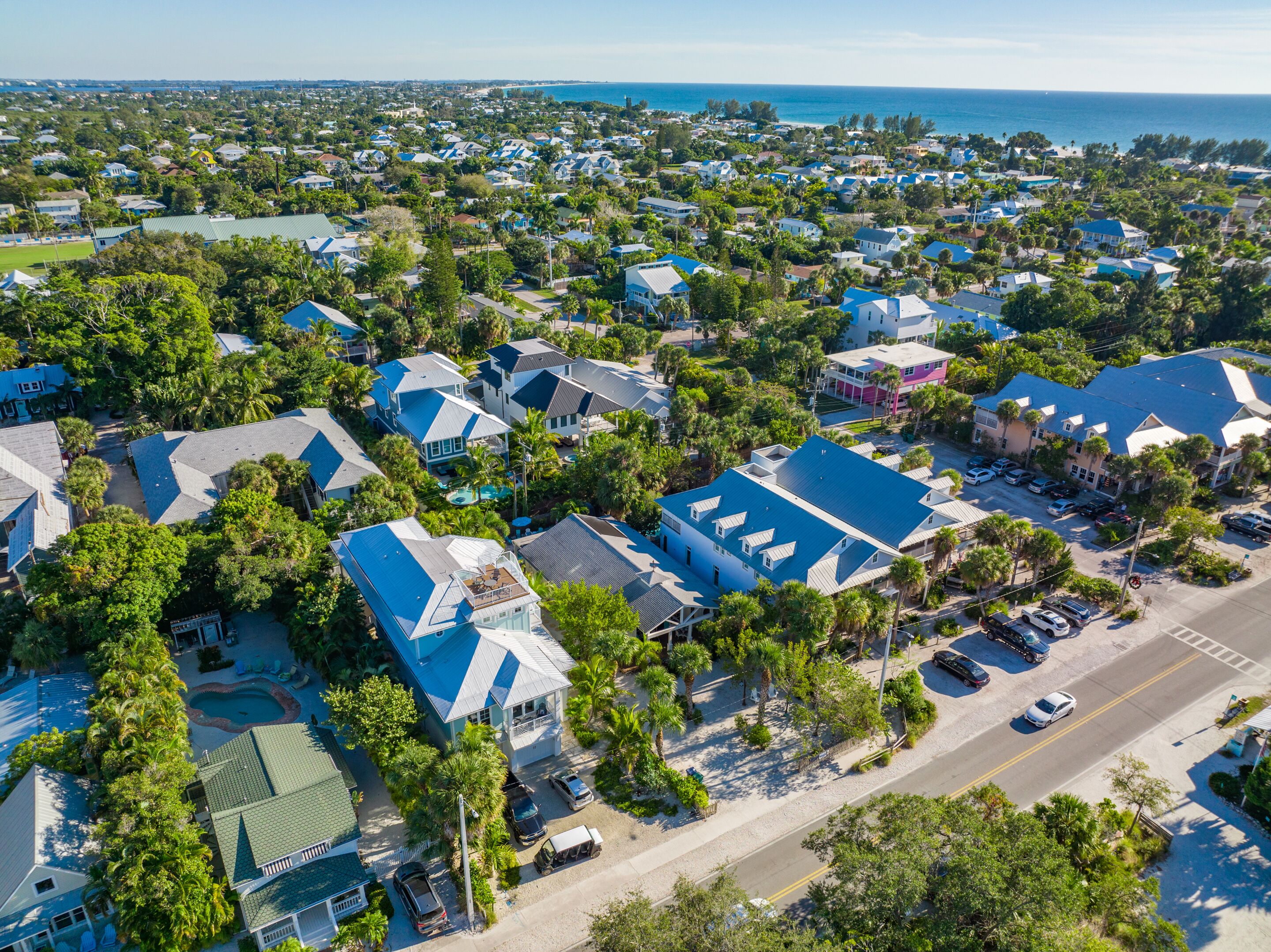 An aerial view of a residential area with houses, a swimming pool, and a road.