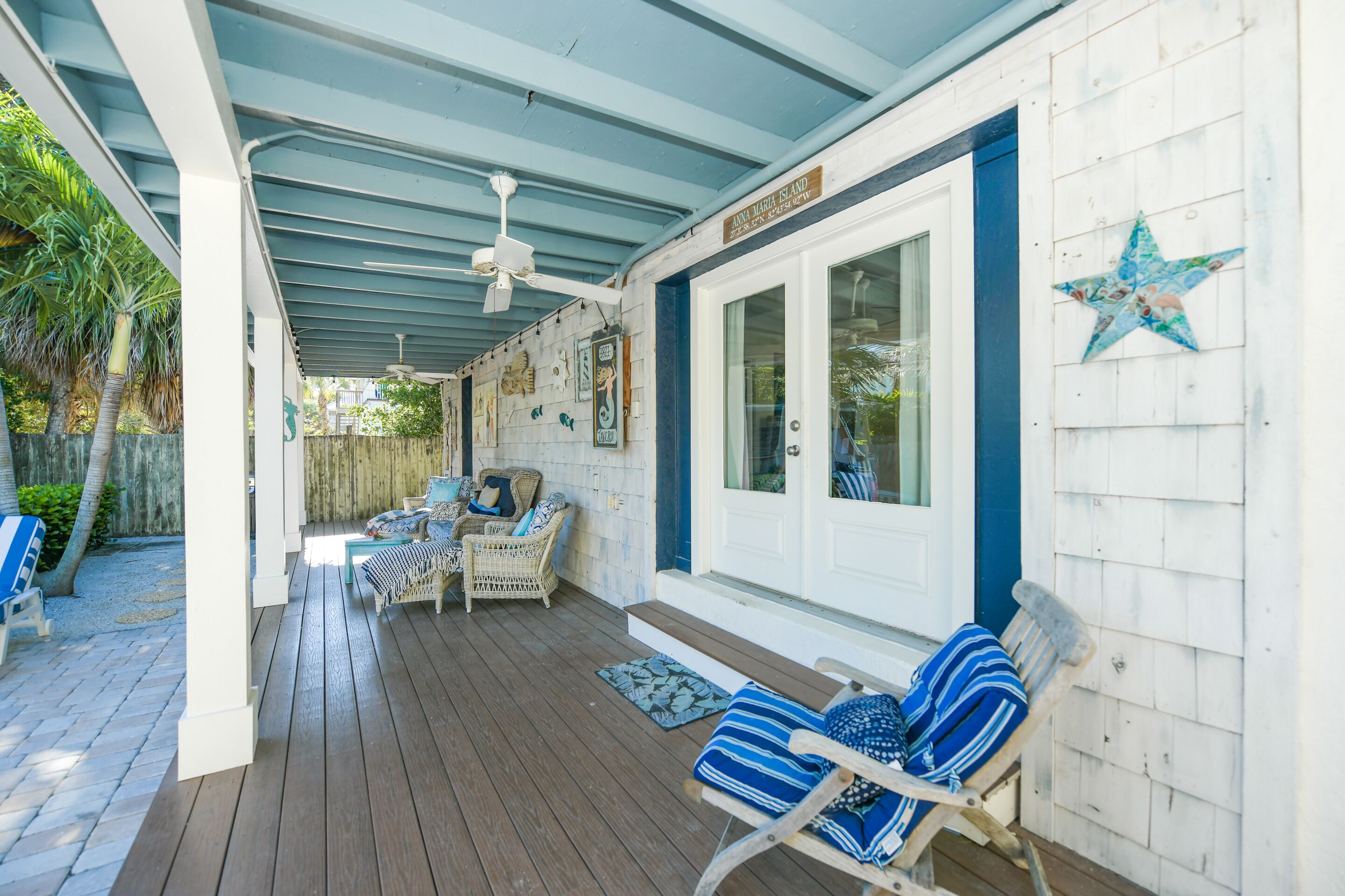 A covered porch with wicker furniture, a ceiling fan, and a star decoration on the wall.